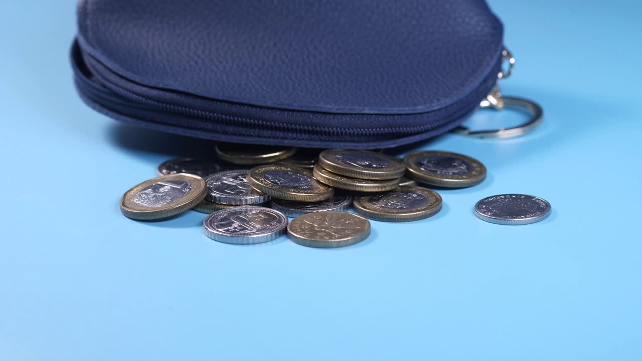 monedas derramadas de un pequeño bolso azul oscuro