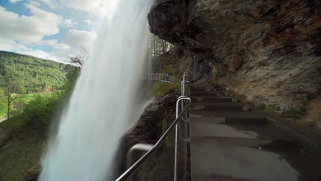 a famous steinsdalsfossen waterfall in the village of steine, norway.  the wall of turbulent whitewater falling off the mountain. the pedestrian bridge is leading under the waterfall
