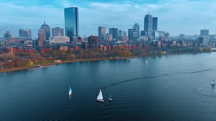 Bellissime barche a vela si muovono dolcemente lungo il paesaggio acquatico del fiume Charles. Vario skyline di Boston, Massachusetts, USA sul lungomare. Prospettiva aerea