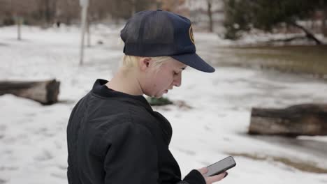 a person stands in the snow, checking their phone