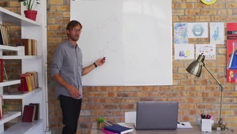 Caucasian-male-teacher-teaching-chemistry-while-looking-at-laptop-in-the-classroom-at-school