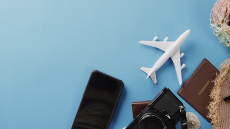 Close-up-of-white-plane-model,-smartphone-and-copy-space-on-blue-background