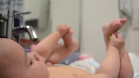 lindo bebé de seis meses jugando con maniquí y sus pies en el baño