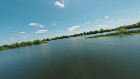 FPV-drone-cinematic-aerial-flyover-tour-of-serene-colorful-Texas-lake-surrounded-by-greenery-on-clear-sunny-day