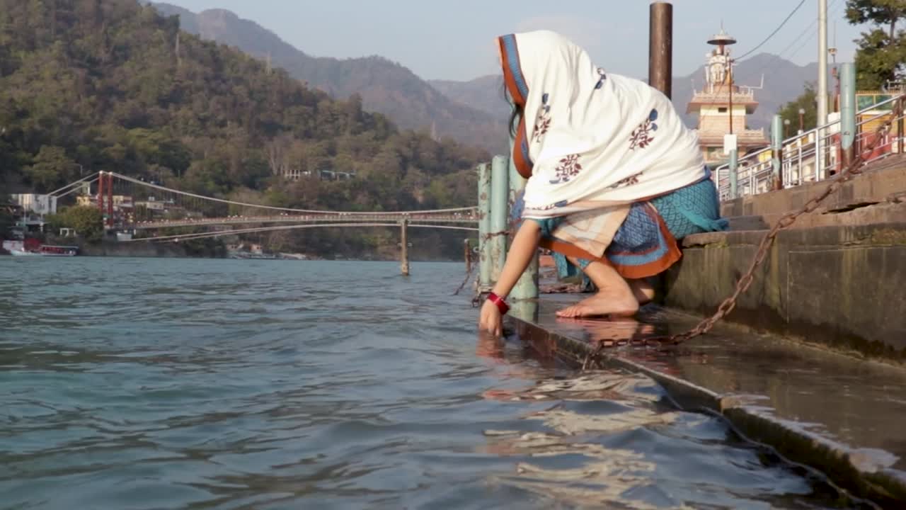 joven india aislada rezando en la orilla del río ganges desde un ángulo diferente se toma un video en la orilla del río ganga rishikesh uttrakhand india