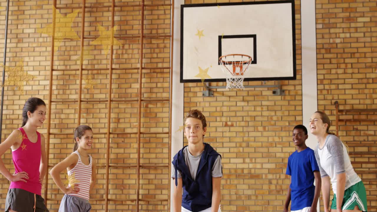 Tienerjongen die een basketbal pakt en naar de basket schiet, klasgenoten kijken toe tijdens de gymles op school