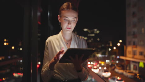woman using tablet at night with city lights