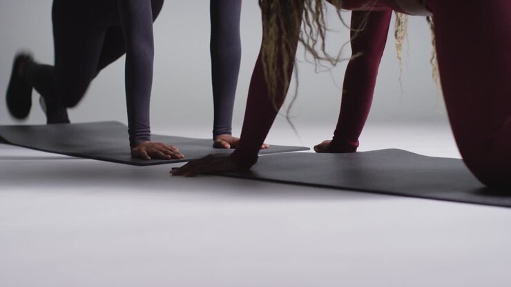 Close Up Studio Shot Of Two Women Wearing Gym Fitness Clothing Facing Each Other Exercising