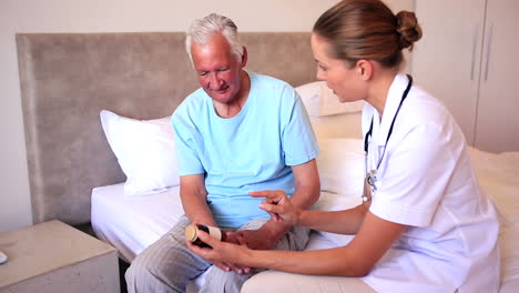 Home-nurse-explaining-medicine-to-elderly-patient