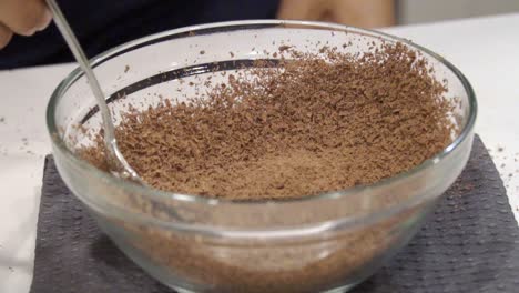 slow motion close up of a girl moving grated chocolate flecks around in a bowl