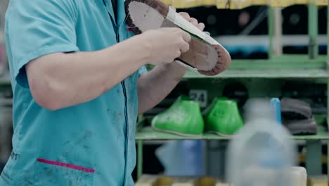 worker applying glue to shoes on a production line in a shoe factory