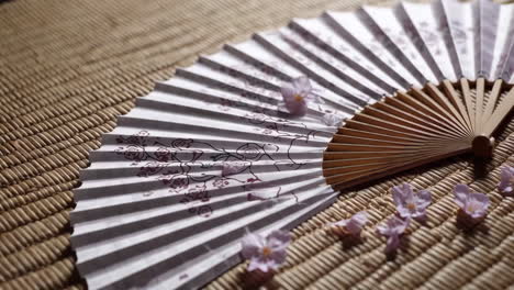 japanese paper fan with cherry blossoms on tatami mat