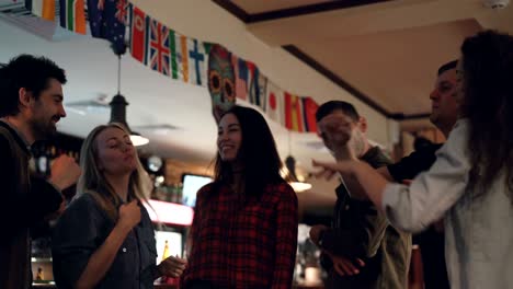 happy careless students in casual clothes are dancing in nice bar. they are laughing and chatting, having fun together. young people enjoying nightlife concept.