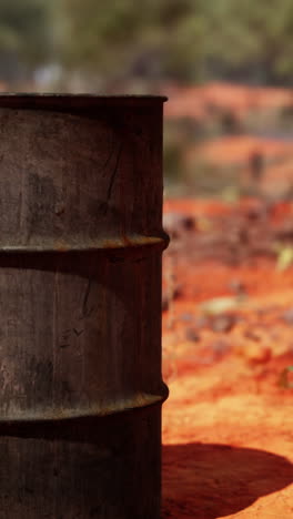 a rusty metal barrel sitting on red dirt