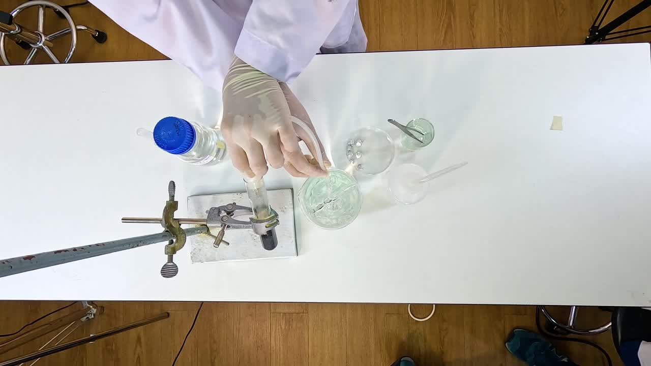 Scientist conducts thermal decomposition of copper carbonate using laboratory equipment on a white table under bright lighting