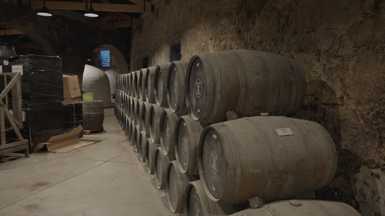 File di botti di vino in rovere invecchiate all'interno del corridoio della cantina in pietra