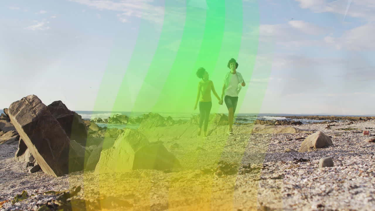 Couple walking on rocky beach with colorful wave animation overlay