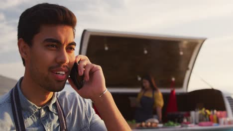 Young-man-talking-on-the-phone-by-food-truck