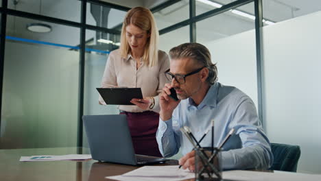 Focused-coworkers-discussing-business.-Woman-bringing-folder-to-businessman