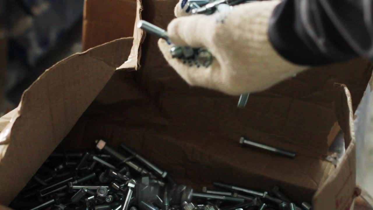 el trabajador con guantes mira los pernos.