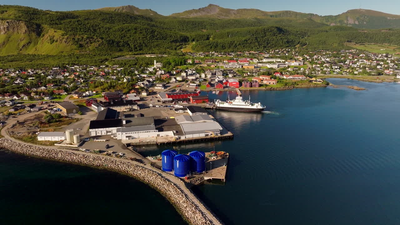 Luftdronebilde av en bilferge som forlater Melbu havn mot Fiskebol. Den vakre kystbyen i Hadsel kommune i Lofoten, Norge