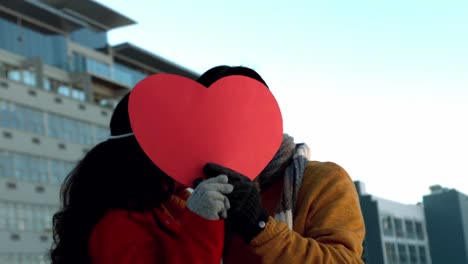 romantic couple hiding themselves behind heart shape