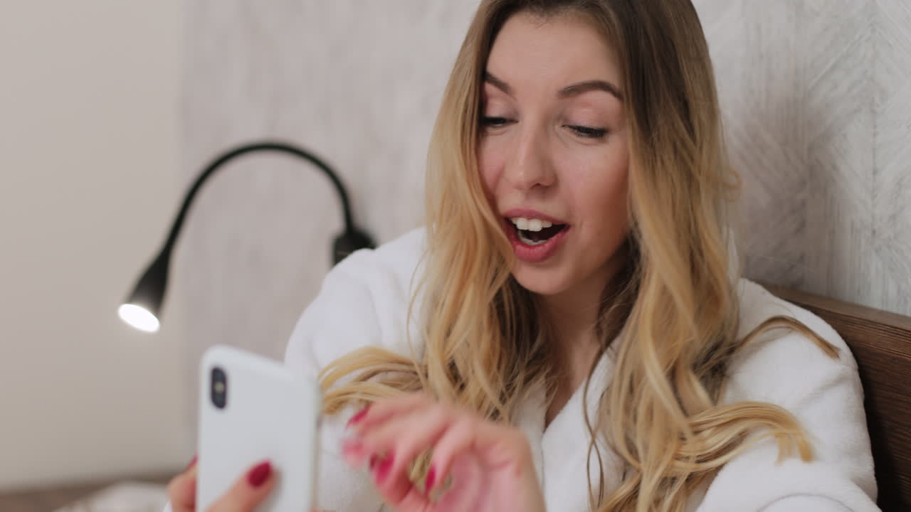 침대에서 전화를 사용하는 여자