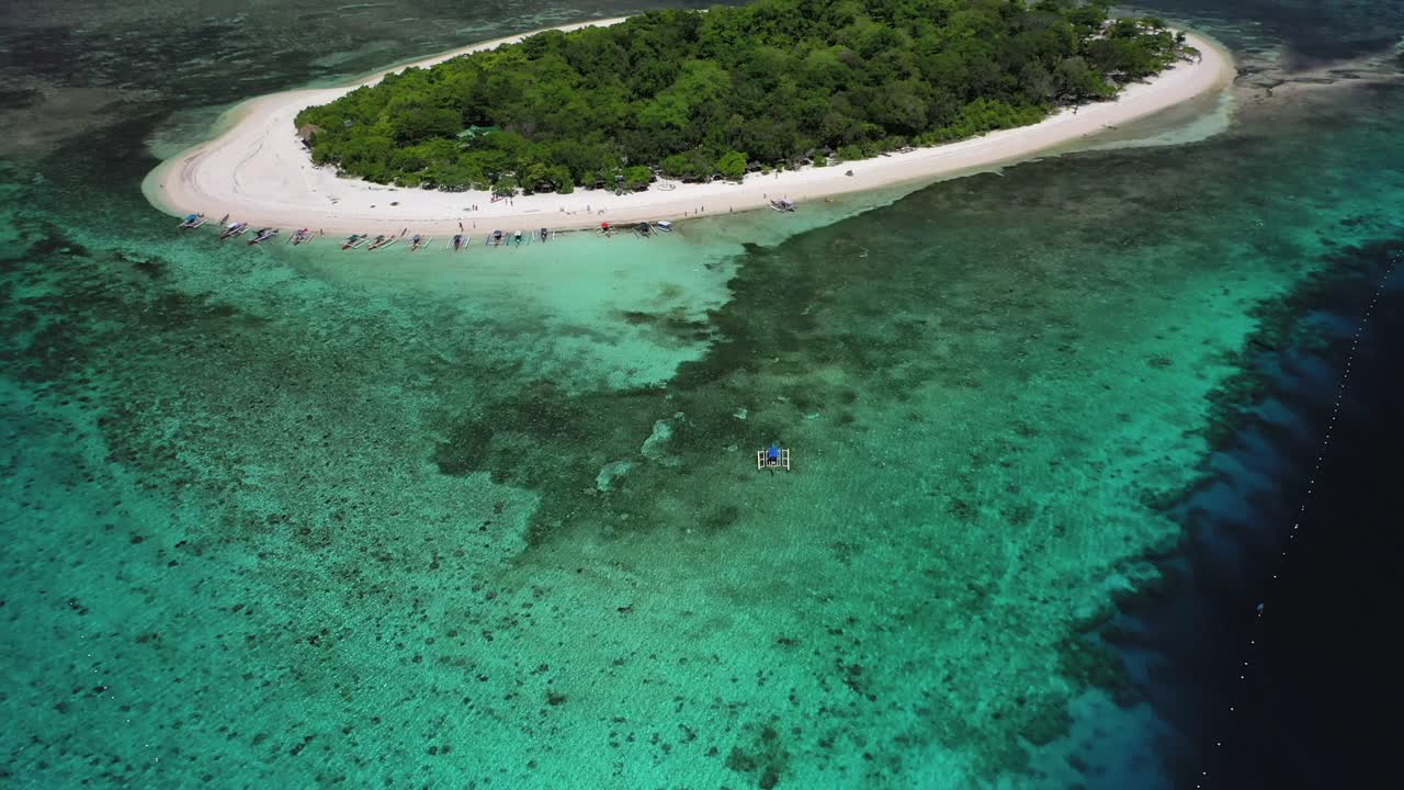 Banca boat approaching Mantigue Island in the Philippines, tilt up aerial