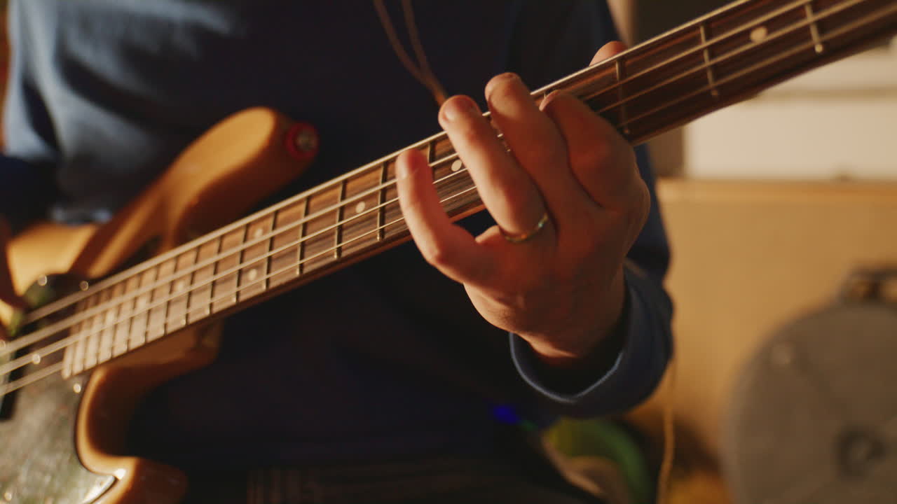 Primo piano statico di dita sulle corde di un basso in un accogliente ambiente da studio