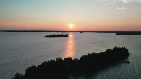 Vista-Aérea-De-La-Isla-De-La-Puesta-De-Sol-Rosa-De-Verano-Que-Se-Refleja-En-El-Agua-Del-Lago-En-Las-Islas-Les-Cheneaux,-Michigan