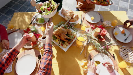 happy diverse male and female friends serving thanksgiving celebration meal in sunny garden