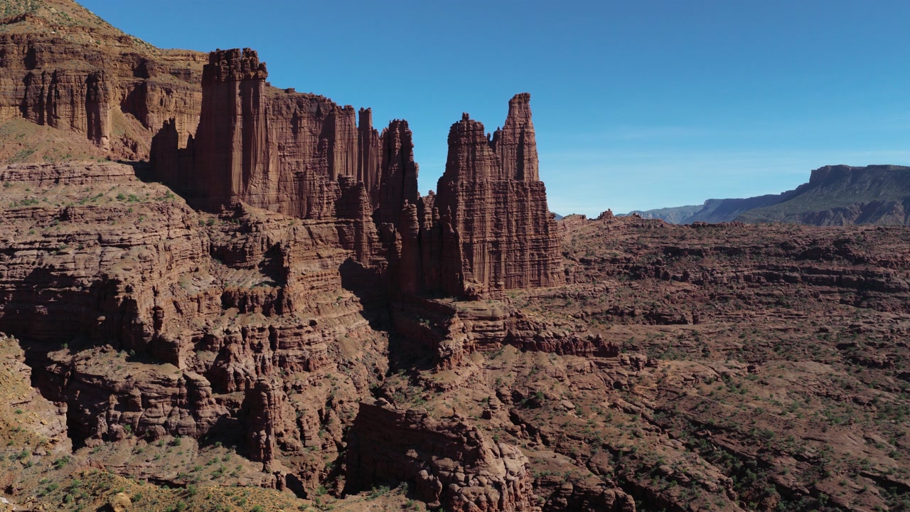 Aerial perspective of Fisher Towers' red sandstone cliffs near Moab, Utah, overlooking a rugged desert canyon landscape. Rising Shot