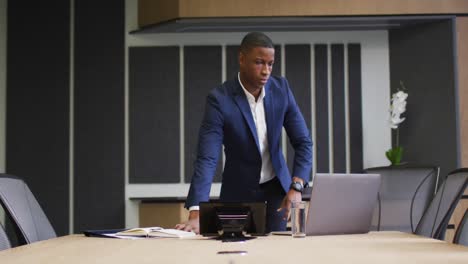 African-american-businessman-using-laptop-in-conference-room-in-modern-office