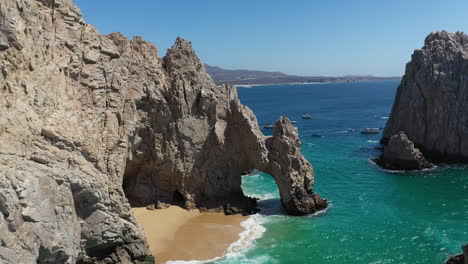 Toma-Aérea-De-El-Arco-Y-Playa-Del-Amor-Revelando-Lentamente-Barcos-En-El-Océano-En-Cabo-San-Lucas-México