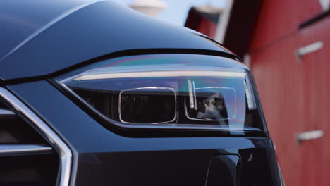 Close-up-of-car-headlights-turning-on-ignition-of-a-silver-grey-metallic-Audi-S5-sports-car-coupé-getting-ready-for-adventure-driving-away-road-trip-starts-near-docks-harbor-light-igniting