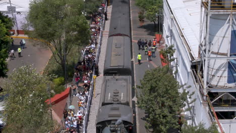 steam train arriving at station with large crowd of spectators