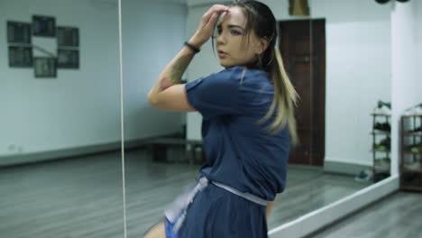 slow motion shot of caucasian female dancer choreographer performing contemporary dance routine against a mirror wall in a dance studio