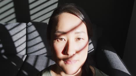 집 에서 창문 근처 의 소파 에 앉아 있는 사려 깊은 아시아 여자