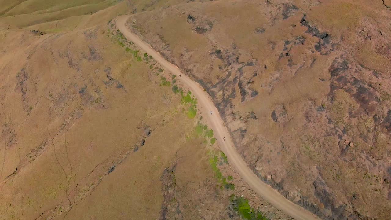 vista aérea siguiendo a ciclistas de montaña bajando un paso de montaña 60fps