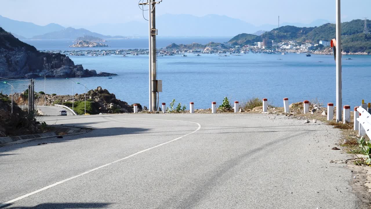 바다 근처의 베트남의 도로에서 오토바이를 운전하는 카이트 서핑 서핑 보드는 자전거 서핑 랙에 부착되어 있습니다.