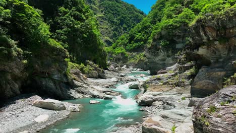 vuelo lento del avión no tripulado sobre un hermoso arroyo que fluye por las verdes colinas del parque nacional durante un día soleado - parque nacional taroko, taiwán