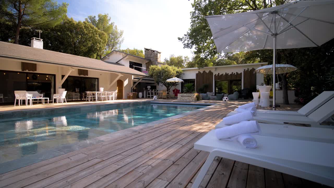 Slow establishing shot of towels rolled up laying on a sun lounger at a pool