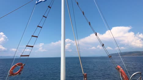 Front-view-of-sailing-ship-mast-on-blue-Mediterranean-sea-in-Sithonia,-Greece-in-4k-in-slow-motion-with-two-kisby-rings