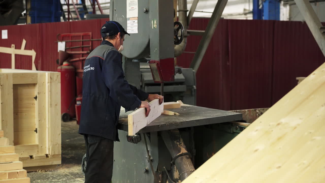 공장에서 나무를 잘라내기 위해 밴드 사를 사용하는 노동자