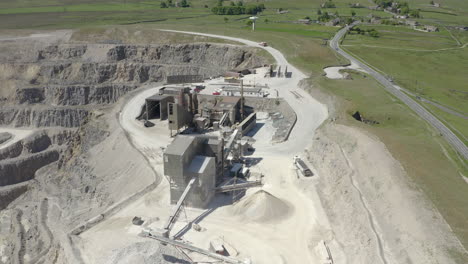 an aerial view of a working asphalt quarry building with the quarry cut to the left of frame, yorkshire, uk