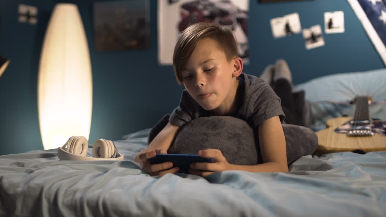 Boy Playing Smartphone in Bedroom