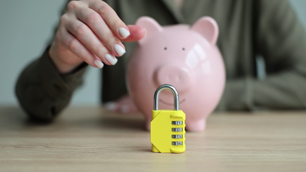 A hand secures a pink piggy bank with a yellow combination padlock, symbolizing financial protection