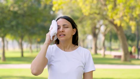 indian woman wiping her sweat using a towel after a workout in a park in morning