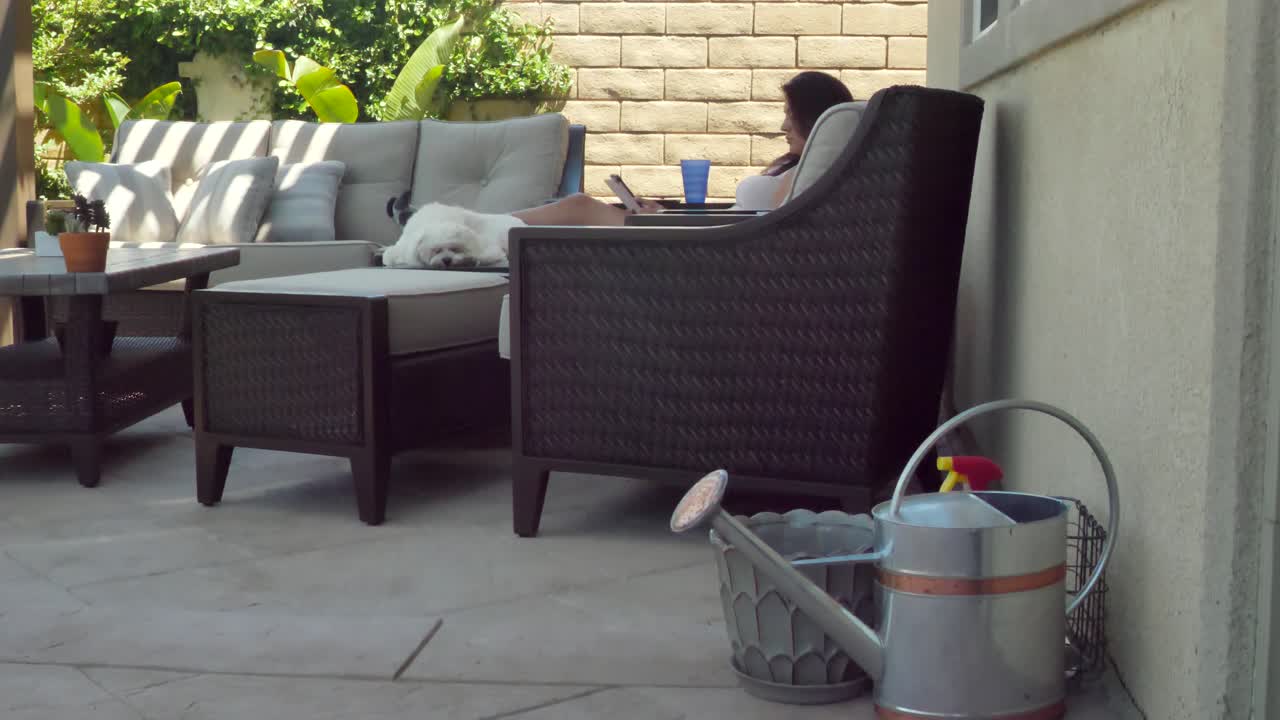 Relaxing female - sleepy dog reading tablet in home garden