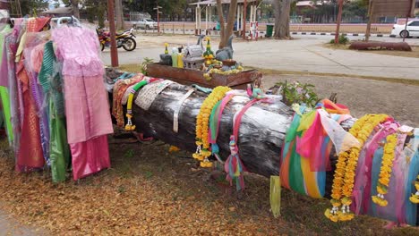 vestidos multicolores colgados en el parque con troncos de árboles horizontales decorados con lei y coloridas tiras de tela